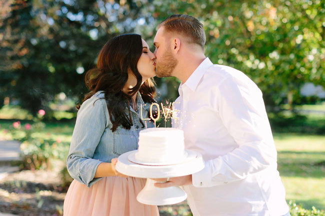 What To Do When You Get Engaged A newly engaged couple holding a cake with a sparkling LOVE topper